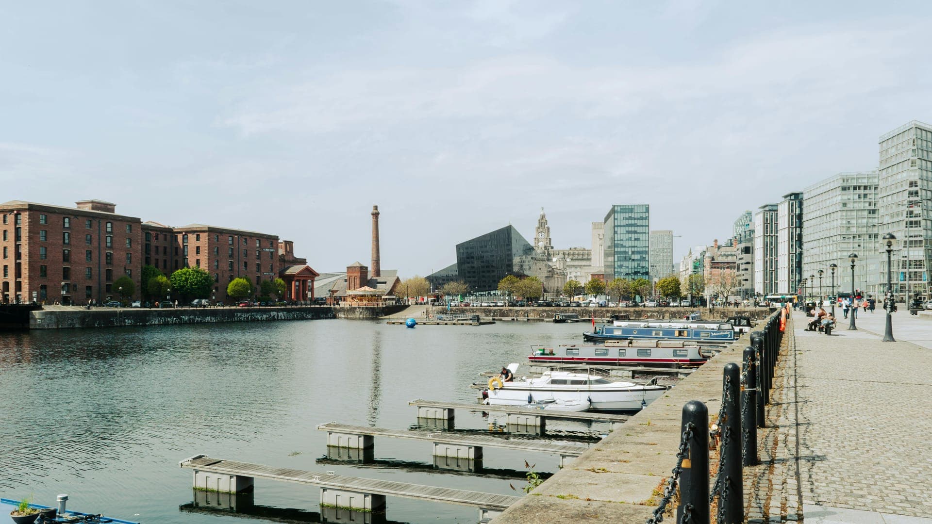 A waterfront view of a marina with boats, historic buildings, and modern architecture along the river.
