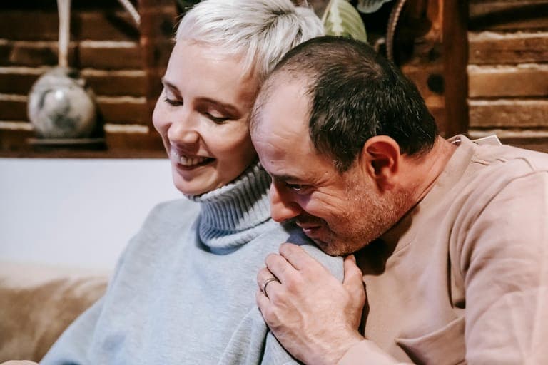 A man embraces a woman from behind while they share a joyful moment together.